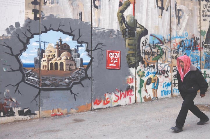 A man walks past graffiti representing the reconstruction of Gaza, on a section of Israel’s separation barrier, in Bethlehem in the occupied West Bank, on Wednesday.—AFP