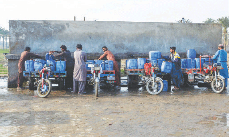 Vendors load cans of drinking water on their motorcycle carts, as they fill them from a private water supply plant in Jacobabad.—AFP Vendors load cans of drinking water on their motorcycle carts, as they fill them from a private water supply plant in Jacobabad.—AFP