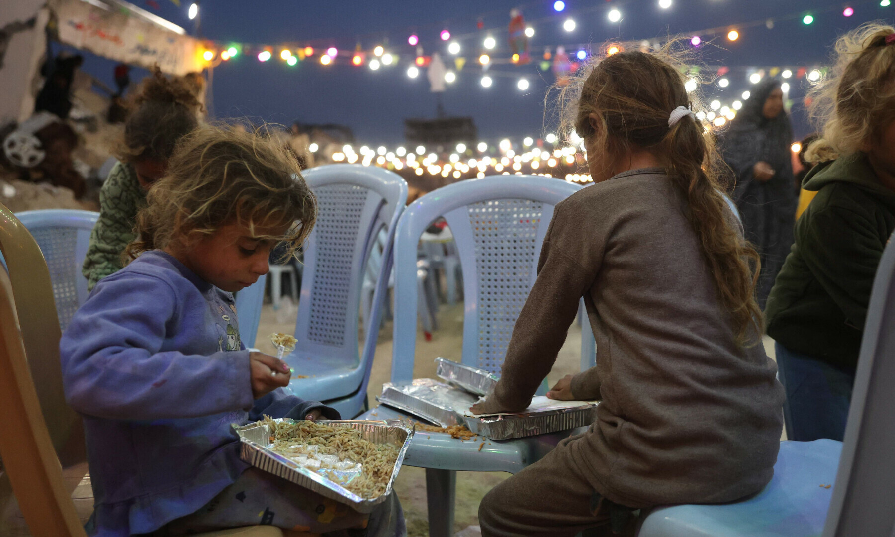 Palestinian children eat their food during a group Iftar meal, the evening meal with which Muslims end their daily fast at sunset, in Gaza City on March 6, 2024. — AFP