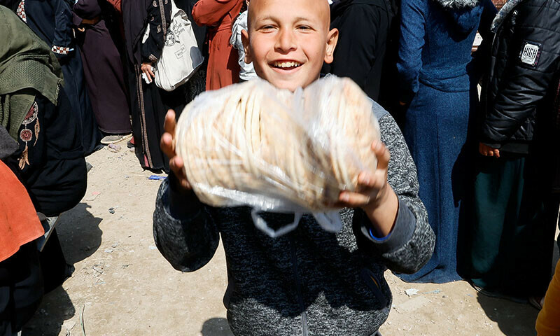 A Palestinian child reacts as he and others gather to receive bread from a bakery, in Khan Younis, in the southern Gaza Strip on March 9. &mdash; Reuters