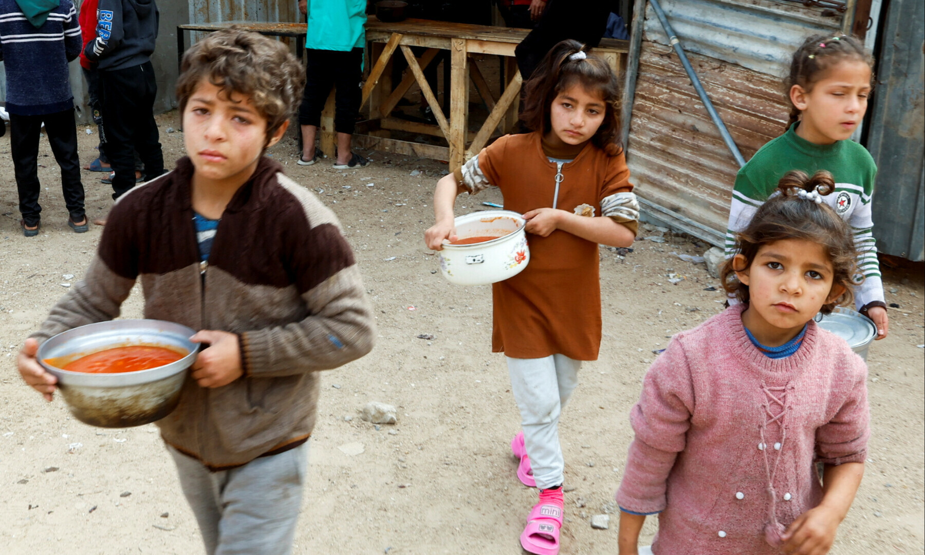 Palestinian children walk after receiving food cooked by a charity kitchen during Ramazan in Khan Younis, in the southern Gaza Strip, on March 9, 2025. — Reuters/Hatem Khaled