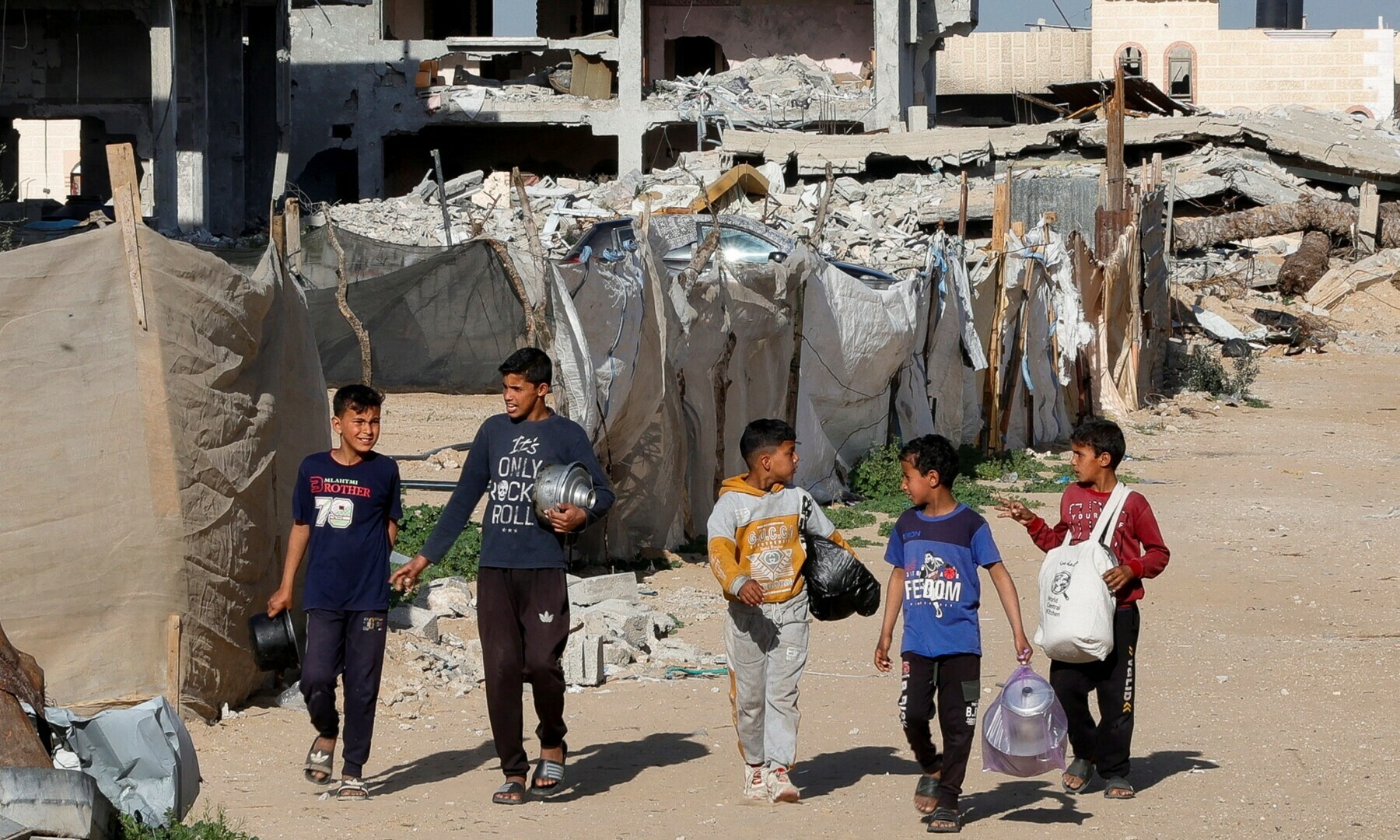 Palestinian children walk with containers to receive food cooked by a charity kitchen during Ramazan, in Rafah, in the southern Gaza Strip on March 13, 2025. — Reuters/Hatem Khaled