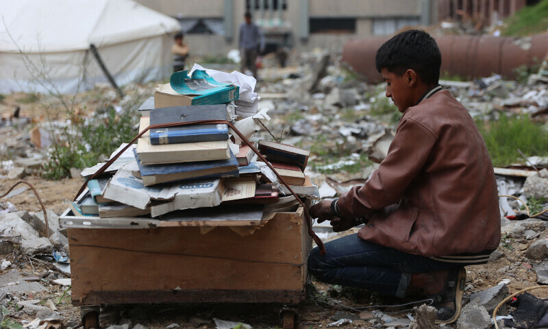 A displaced Palestinian collects books, from the destroyed Islamic University to use as fuel to cook food, in Gaza City on March 21, 2025. — AFP