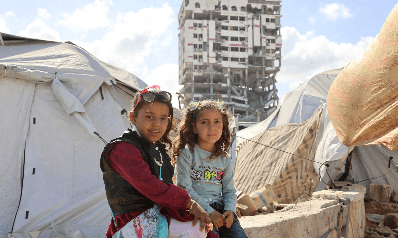 Palestinian girls sit outside their makeshift tent during Eidul Fitr, which marks the end of Ramazan, in Gaza City on March 30, 2025. — AFP