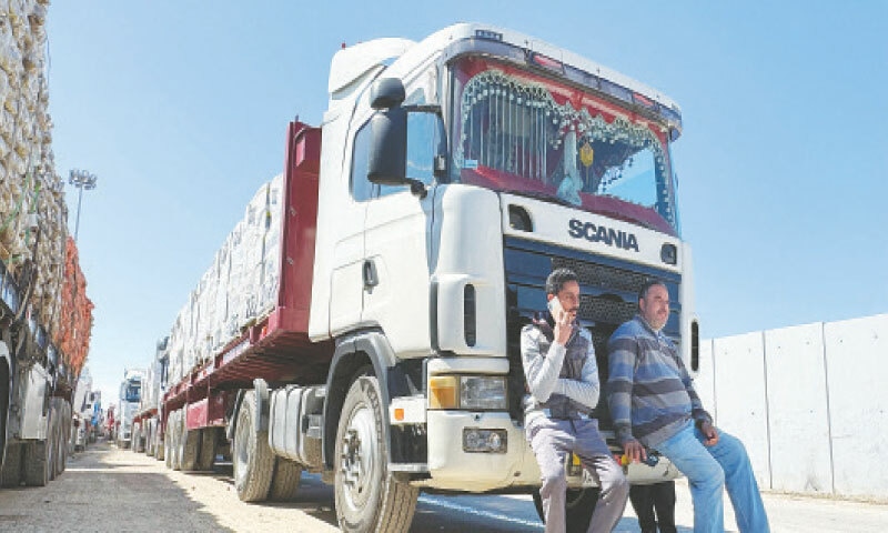 DRIVERS wait next to aid trucks on the Egyptian side of the Rafah border crossing with Gaza, on Sunday.—AFP