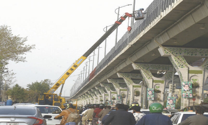 A worker paints the railing of the metro track near Shamsabad in Rawalpindi on Tuesday. &mdash; Photo by Mohammad Asim