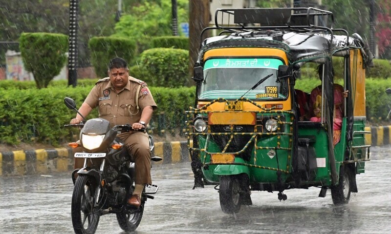 Commuters make their way along the road as it rains in Amritsar, India on April 11. — AFP