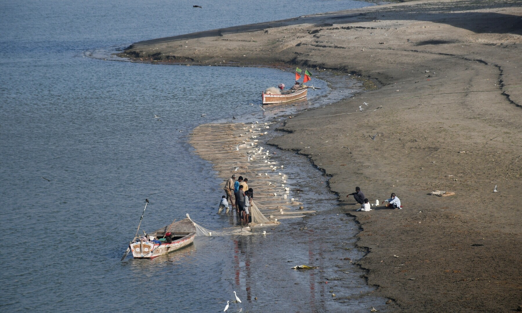Fishermen clear a fishing net in the water on the partially dried up riverbed of the Indus River in Hyderabad on April 25, 2025. &mdash; Reuters/Yasir Rajput