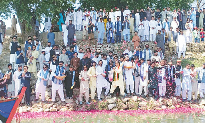 People from different sections of society throw rose petals in Indus River to raise awareness about pollution and preservation of water resources. — Dawn