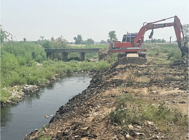 GUJRAT: Heavy machinery is at work to desilt the open drain near railway line between Kalara and Gurala. &mdash; Dawn