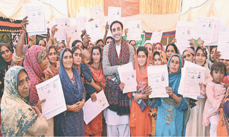 SUKKUR: PPP Chairman Bilawal Bhutto-Zardari, along with flood-hit women, poses for a group photo after distributing land titles and ownership papers among them.&mdash;PPI