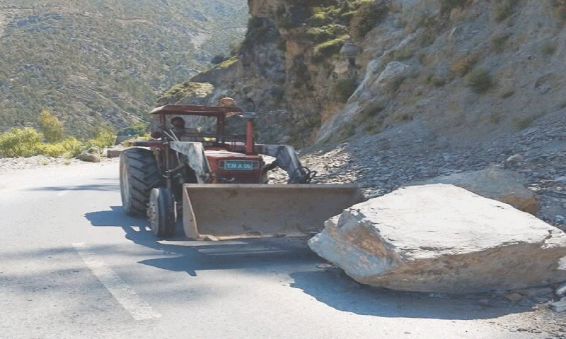 A boulder partially blocking Khar-Barang Road in Bajaur being removed on Sunday. &mdash; Dawn
