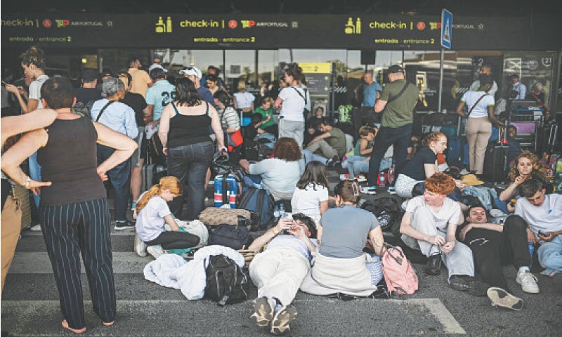 PEOPLE wait outside Humberto Delgado airport with their luggage.—AFP PEOPLE wait outside Humberto Delgado airport with their luggage.—AFP