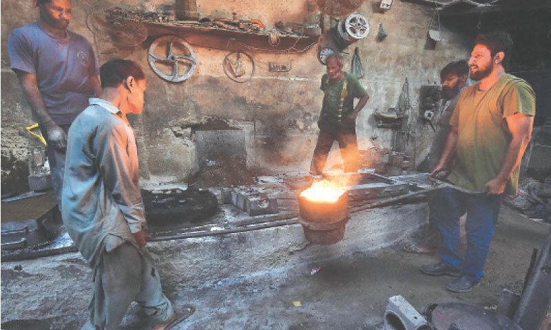 Workers remove molten iron from the furnace at an iron factory in the Garden area on the eve of International Labour Day.—Shakil Adil / White Star