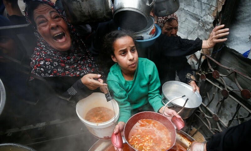 Palestinians receive food cooked by a charity kitchen, in Beit Lahiya, northern Gaza Strip on April 28. — Reuters