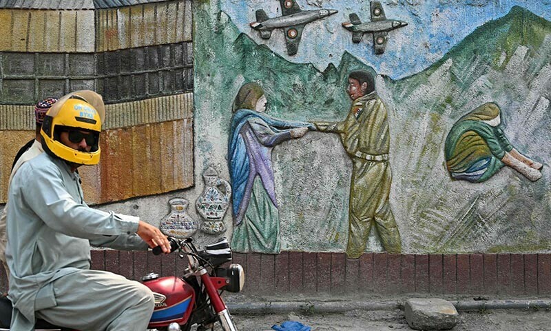 A motorist rides past a wall graffiti along a street in Muzaffarabad on May 1, 2025. — AFP