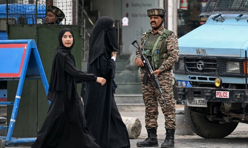 Indian paramilitary personnel stand guard as schoolgirls walk along a street in Srinagar on May 1, 2025. — AFP