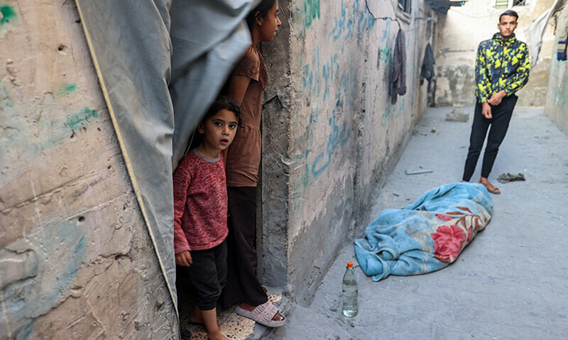 People stand near the shrouded body of a person killed in an Israeli strike that hit a building in the Bureij camp for Palestinian refugees in the central Gaza Strip on May 2. — AFP