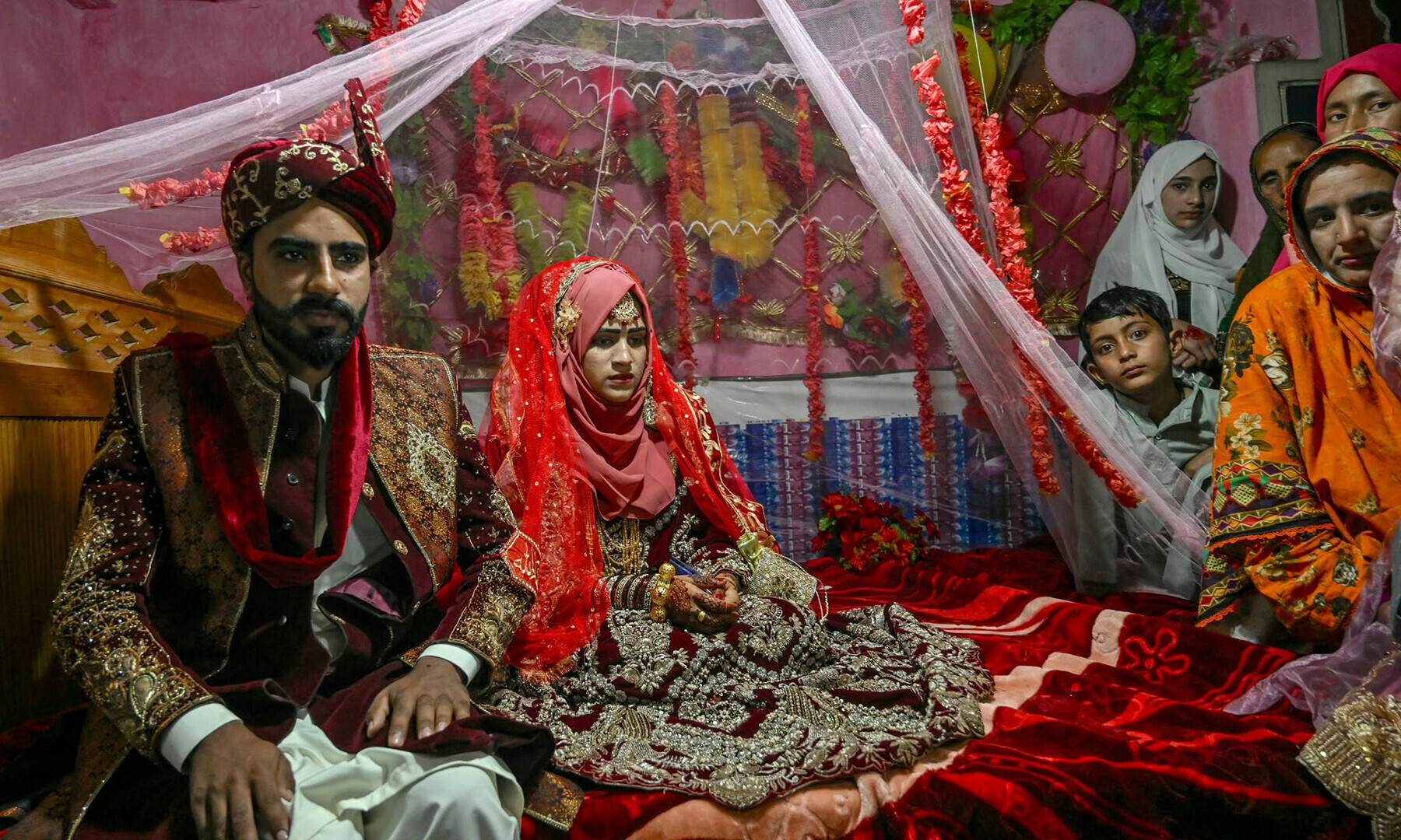 Groom Chaudhry Junaid (L) sits with his bride, Rabia Bibi, during their wedding ceremony in Ashkot village on the Line of Control (LoC) in Neelum Valley, a district of Azad Jammu and Kashmir, on May 3. — AFP