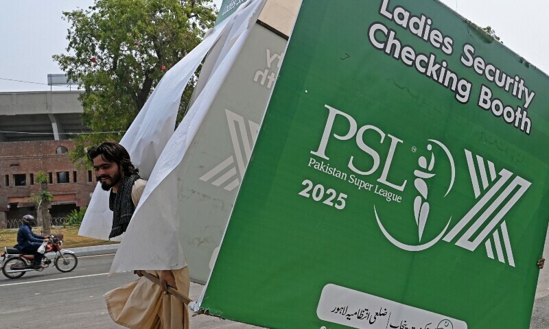 A worker removes a hoarding outside the Gaddafi Cricket Stadium, one of the venues for the Pakistan Super League (PSL), in Lahore on May 9. &mdash; AFP.