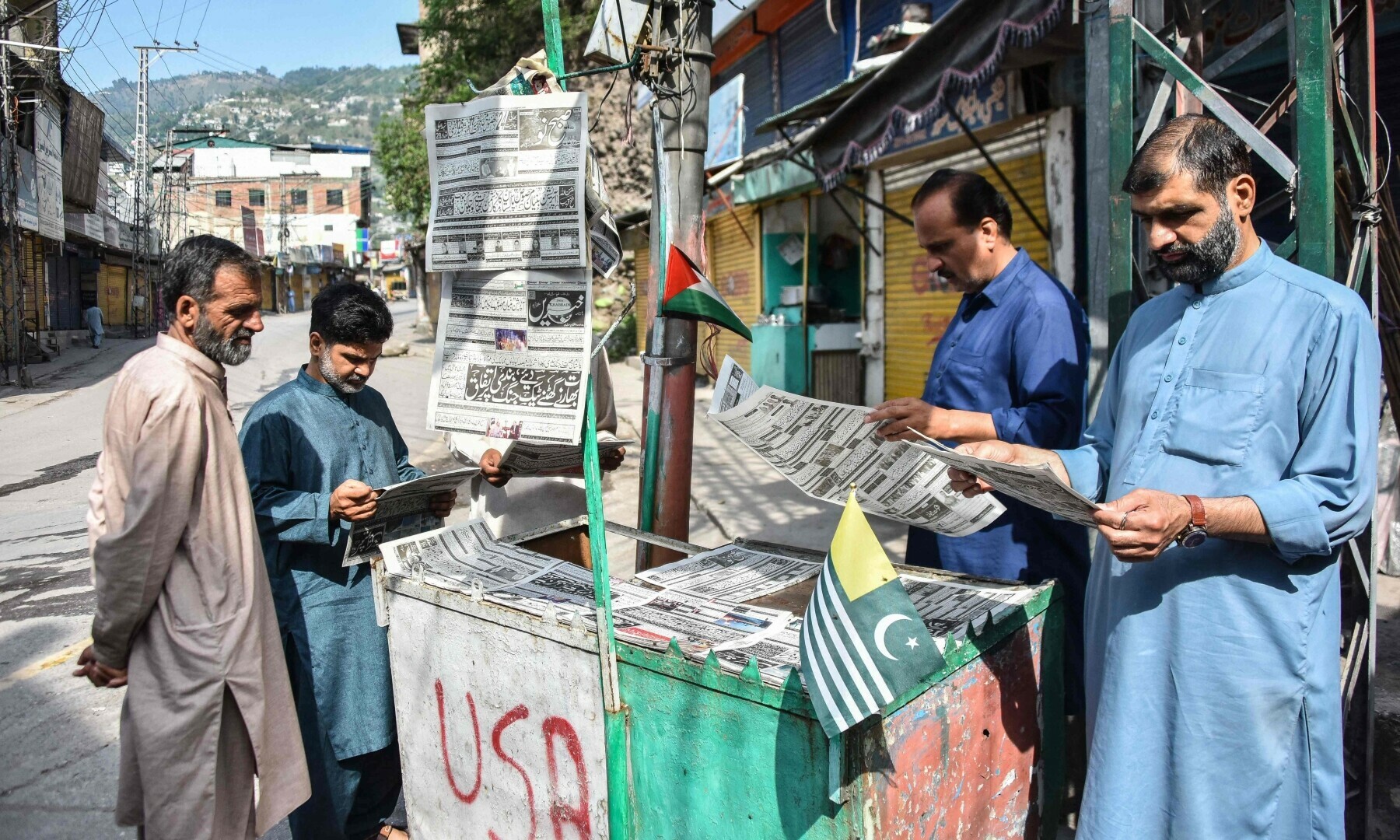  Residents read morning Urdu newspapers with the headline &lsquo;The ceasefire between Pakistan and India&rsquo; on a roadside in AJK&rsquo;s Muzaffarabad on May 11, 2025. &mdash; AFP 