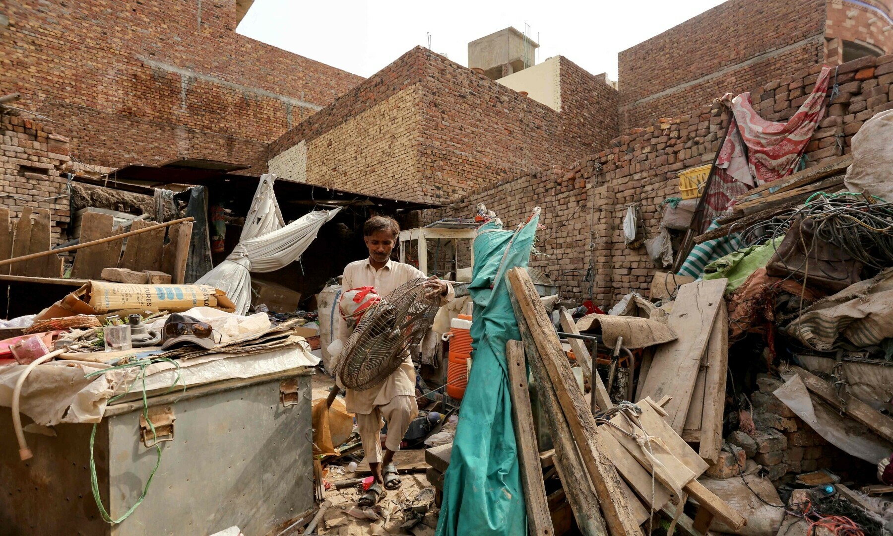 A man collects his belongings on Sunday after a dust storm damaged his house in Multan.&mdash;AFP