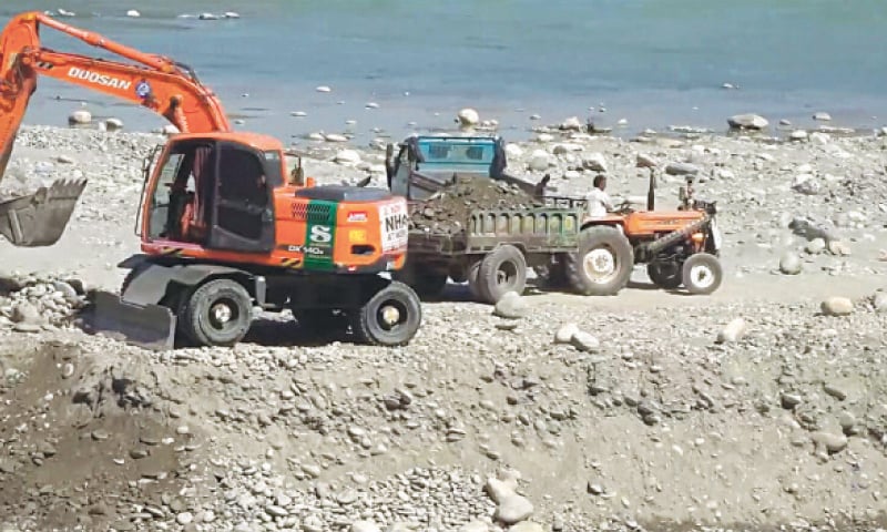   دریائے سوات کے کنارے ایک کھدائی کرنے والی گاڑی، ٹیکٹر ٹرالی میں بجری بھر رہی ہے— ڈان فائل فوٹو  