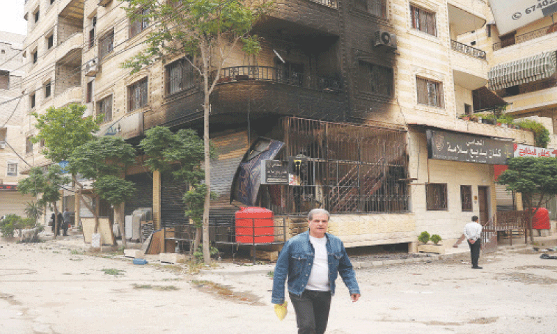A man walks past a partially burnt building following sectarian clashes in Ashrafiyat Sahnaya, near Damascus, on Thursday.—AFP A man walks past a partially burnt building following sectarian clashes in Ashrafiyat Sahnaya, near Damascus, on Thursday.—AFP