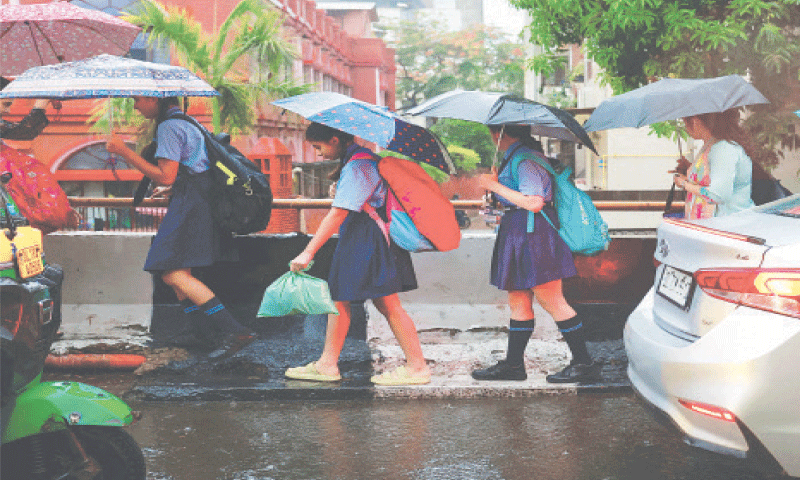 CHILDREN use umbrellas to cover themselves from the rain as they walk to school on Friday.—Reuters