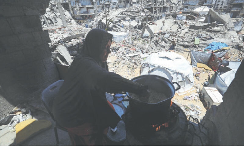 A woman cooks amid the rubble of houses in the Jabalia camp.—Reuters