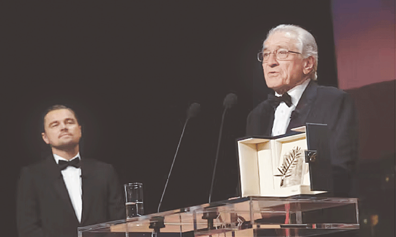 Leonardo DiCaprio, left, looks on as Robert De Niro accepts his Honorary Palme d’Or during the 78th Cannes International Film Festival on May 13, 2025. De Niro critiqued the new proposed tariffs saying, ‘you can’t put a price on connectivity.’ | Photo by Joel C Ryan/Invision