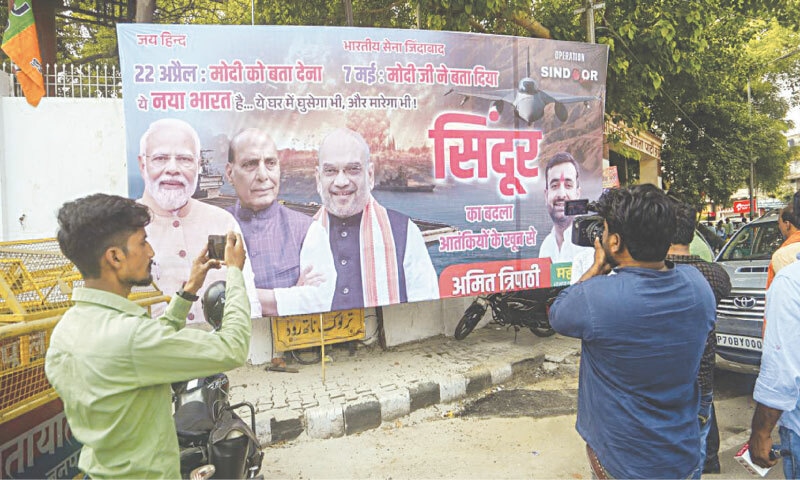 People stand near a poster outside the BJP office in Lucknow, celebrating ‘Operation Sindoor’ 
| Press Trust of India