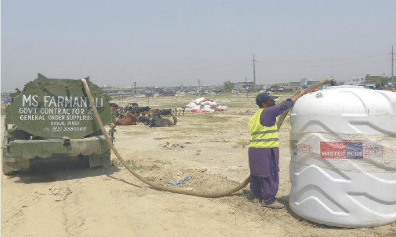 A worker is filling a water tank at the market.