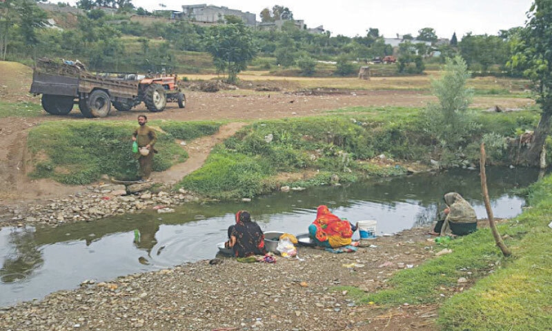 Local women wash clothes in Bothkhatta stream. &mdash; Dawn