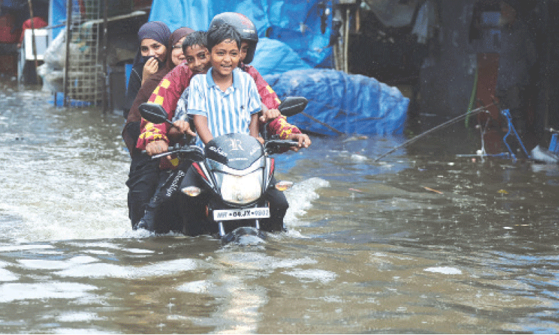 PEOPLE ride a motorbike through a waterlogged street in Mumbai following heavy rains, on Monday.—Reuters PEOPLE ride a motorbike through a waterlogged street in Mumbai following heavy rains, on Monday.—Reuters