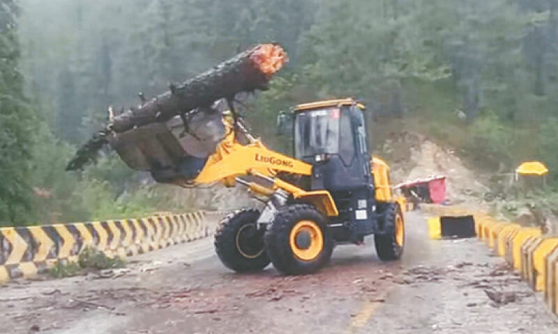 A machine removes a tree uprooted by strong winds and rain in Galyat, Abbottabad, on Tuesday. &mdash; PPI