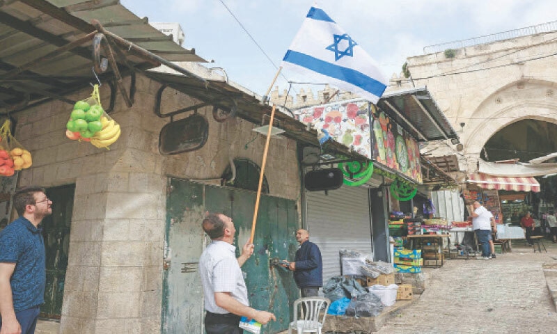 A MAN removes an Israeli flag from the top of a shop owned by a Palestinian as another person uses a grinder on the lock of his shop that was damaged by Israeli right-wing activists on Monday during a flag march to mark Jerusalem Day. The day recalls the capture of the city’s eastern sector by Israel during the 1967 war.—AFP A MAN removes an Israeli flag from the top of a shop owned by a Palestinian as another person uses a grinder on the lock of his shop that was damaged by Israeli right-wing activists on Monday during a flag march to mark Jerusalem Day. The day recalls the capture of the city’s eastern sector by Israel during the 1967 war.—AFP
