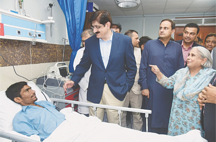 Chief Minister Murad Ali Shah talks with a patient alongside Health Minister Dr Azra Fazal Pechuho, Mayor Murtaza Wahab and others during the hospital visit. &mdash;Dawn