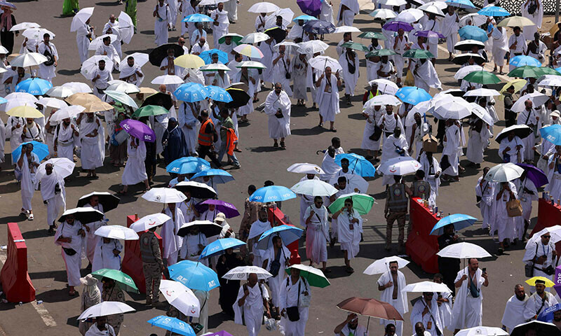 Pilgrims holding umbrellas to protect themselves from the heat walk toward Saudi Arabia’s Mount Arafat, also known as Jabal al-Rahma or Mount of Mercy, during the climax of the Haj pilgrimage on June 5. — AFP