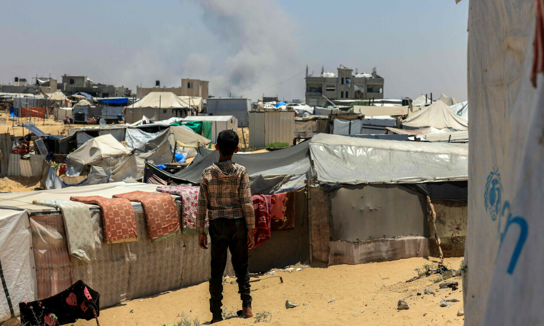A Palestinian child looks on as smoke billows in the distance during Israeli bombardment in Rafah, in the southern Gaza Strip on June 11, 2025. — AFP