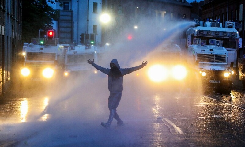 Riot Police use a water cannon in an attempt to disperse protestors gathered for a thrid night of anti-immigration demonstrations, in Ballymena, Northern Ireland, on June 11. — AFP