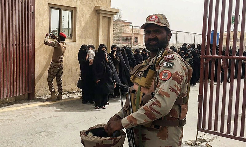 Security personnel stand guard as pilgrims evacuated from Iran cross the Pakistan-Iran border in Taftan on June 16. — AFP