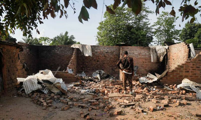 ایک شخص بندوق برداروں کے حملے کے بعد جلے اور تباہ شدہ مکان کے سامنے کھڑا ہے، فوٹو  — رائٹرز