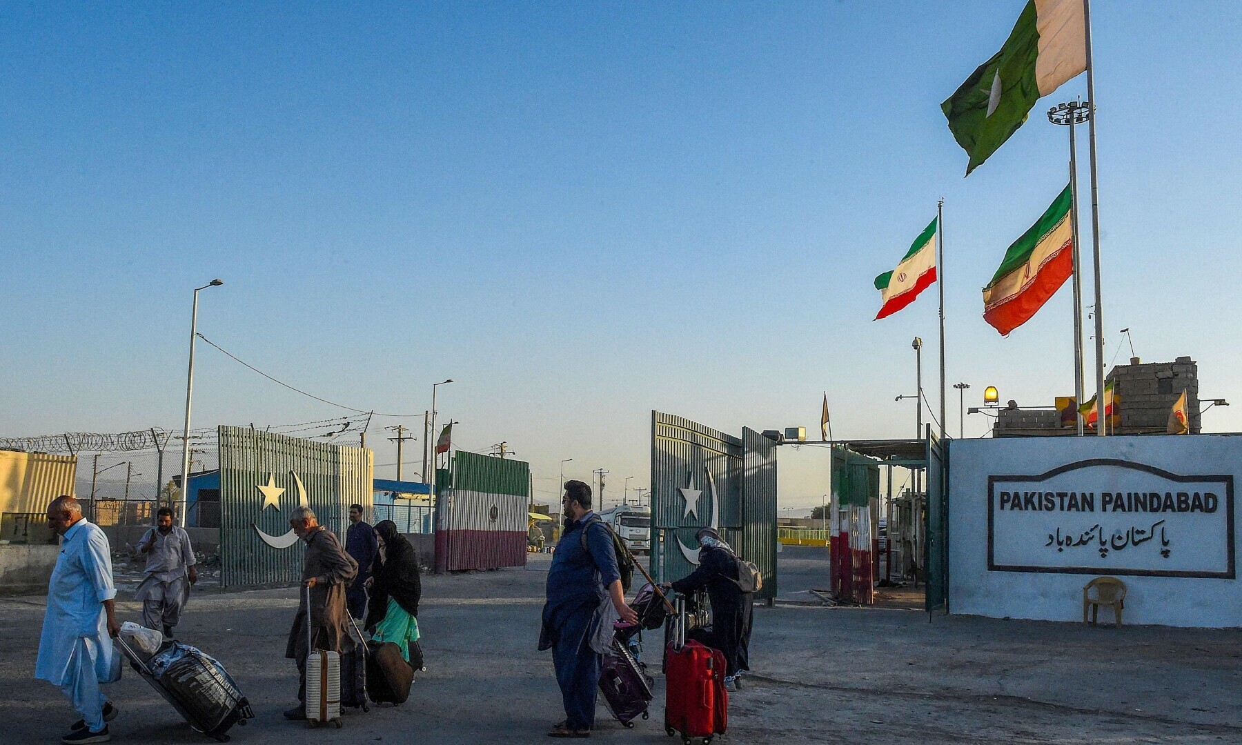 Pakistani pilgrims evacuated from Iran walk across the Pakistan-Iran border at Taftan, in Balochistan, June 18. — AFP