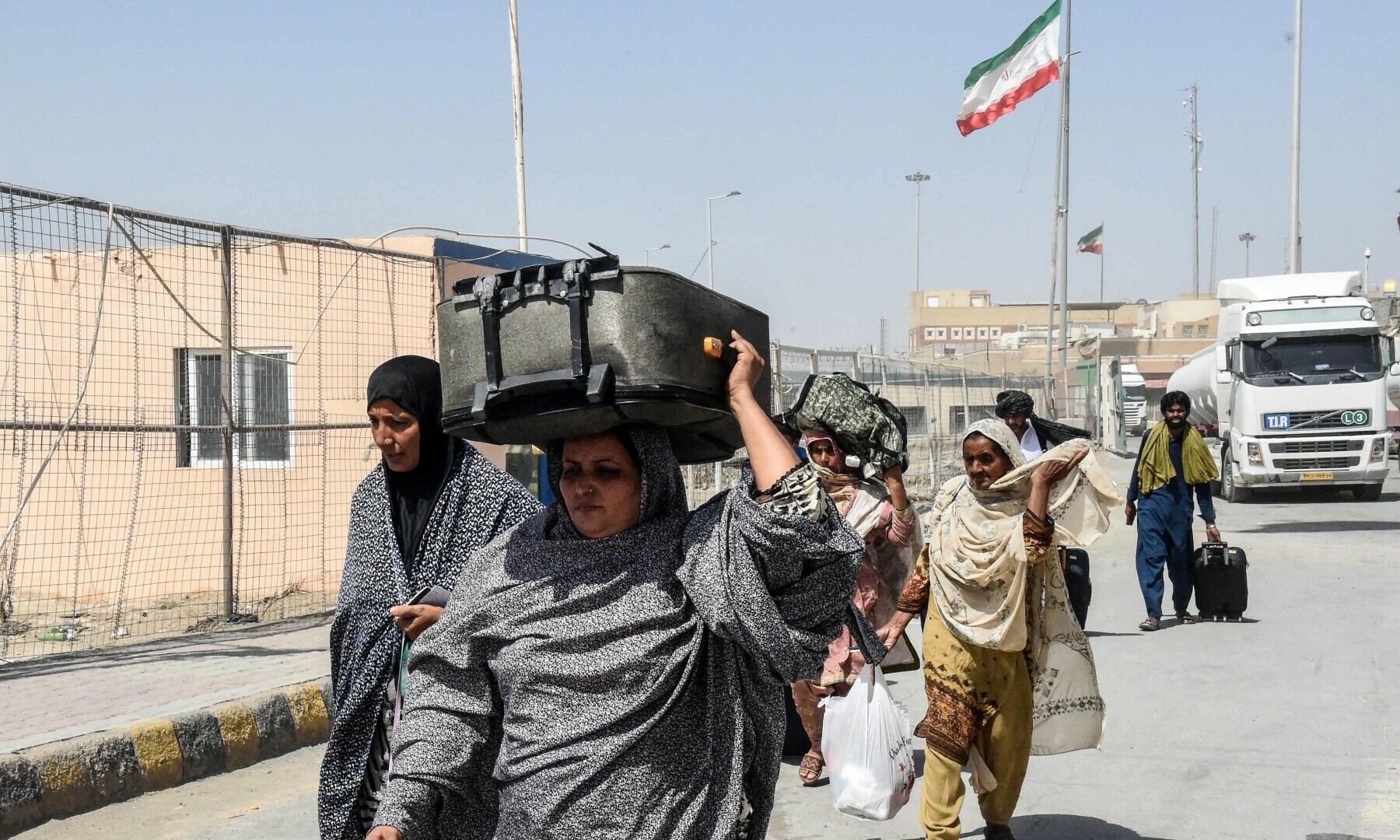  Pakistani pilgrims carrying their belongings walk across the Pakistan-Iran border after returning from Iran in Taftan, Balochistan, June 19. — AFP 