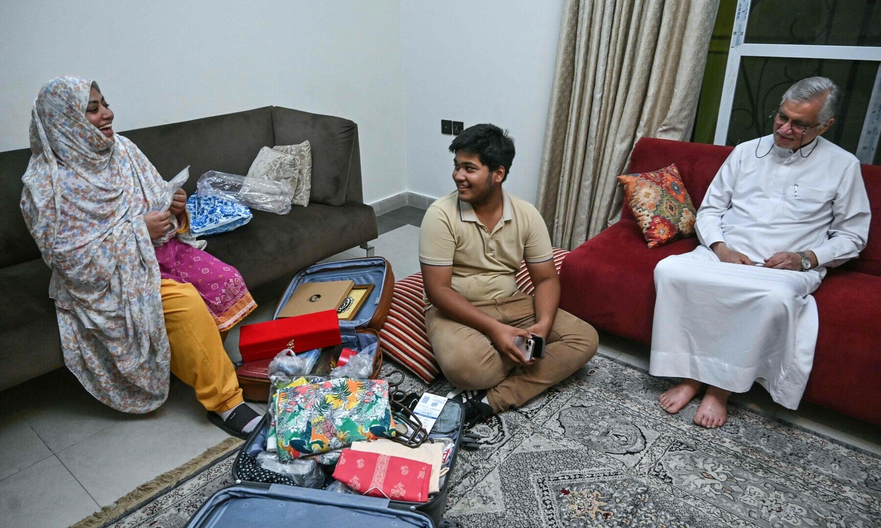  Samreen Ali (L), a housewife, shows gifts to her son (C) and a family friend after returning from Iran, at her residence in Karachi on June 18. — AFP 