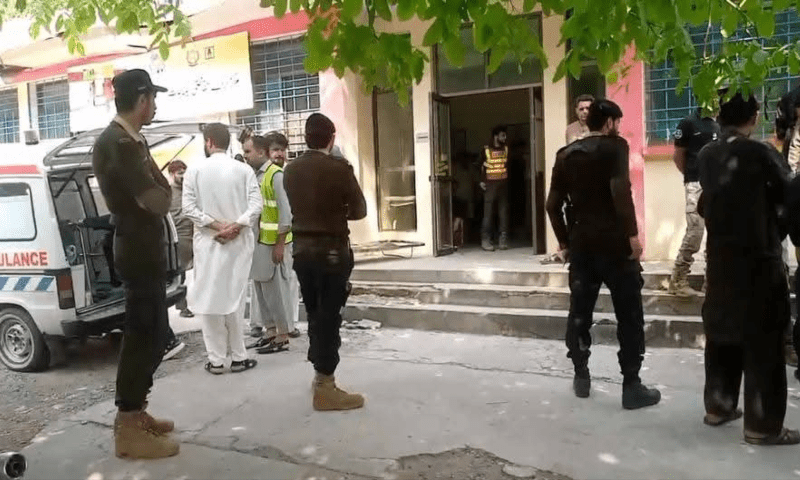 Rescue officials and police stand outside the hospital in Mansehra, June 20. —  Rescue 1122