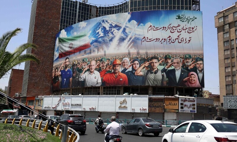 A banner bearing a painting that represents various categories of the Iranian society is deployed against the facade of a building in Tehran, with a message that reads in Farsi: &ldquo; we are all soldiers of Iran&ldquo;, on June 22, 2025. &mdash; AFP