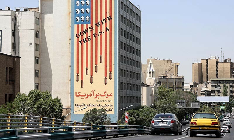Commuters drive along a bridge near a building bearing a landmark anti-US mural in Tehran, on June 22. — AFP