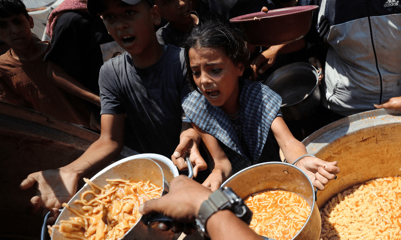 Palestinian children react as they receive food cooked by a charity kitchen, in Gaza City on June 21, 2025. —Reuters